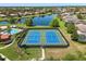 This aerial view showcases tennis courts alongside a tranquil lake and pool at 11316 Rapallo Ln, Windermere, FL 34786