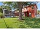 A spacious backyard with artificial grass, a mature shade tree, and a screened-in pool of the two-story red home at 1254 Shelter Rock Rd, Orlando, FL 32835