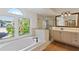 Bright bathroom with a soaking tub, shower, vanity, and large window at 1254 Shelter Rock Rd, Orlando, FL 32835