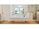 Bright bathroom featuring a soaking tub with jets, a glass-enclosed shower, and a large window overlooking the front yard at 1254 Shelter Rock Rd, Orlando, FL 32835