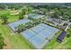 Overhead view of multiple, well maintained tennis courts in a community, surrounded by palm trees and green spaces at 12618 Lakebrook Dr, Orlando, FL 32828