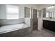 Bright bathroom with tile flooring, a soaking tub, walk-in shower with glass door, and dual vanity sinks at 14572 Black Quill Dr, Winter Garden, FL 34787