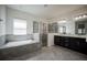 Bright bathroom with tile flooring, a soaking tub, walk-in shower with glass door, and dual vanity sinks at 14572 Black Quill Dr, Winter Garden, FL 34787