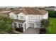 Two-story gray home featuring a brown roof, lush landscaping, and a two-car garage at 14572 Black Quill Dr, Winter Garden, FL 34787