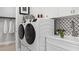 Well-equipped laundry room featuring modern washer and dryer, ample storage, and stylish tile backsplash at 1613 Bellagio Loop, Tavares, FL 32778