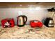 Close-up of a modern kitchen counter with granite countertops, appliances, and red Mickey Mouse-themed items at 2379 Distant Sun Trl, Kissimmee, FL 34747