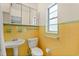 Bright bathroom with vintage yellow tile, pedestal sink, and medicine cabinet storage at 3007 Huntington St, Orlando, FL 32803