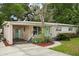 Single-story home with pink exterior, lush landscaping, covered carport, and eye-catching light teal front door at 3007 Huntington St, Orlando, FL 32803