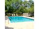 Community swimming pool surrounded by lush landscaping, lounge chairs, and a privacy fence at 3312 Bridgeford Dr, Orlando, FL 32812