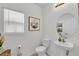 Bathroom with a pedestal sink, toilet, and a decorative mirror, with natural light from the window at 356 Quarry Rock Cir, Kissimmee, FL 34758