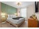 Calming bedroom featuring a queen bed, stylish lighting, dresser, and verdant green accent wall at 4314 Lana Ave, Davenport, FL 33897