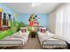 Bright bedroom with twin beds, colorful cartoon mural, and plush bedding at 4314 Lana Ave, Davenport, FL 33897