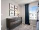 Cozy bedroom offers a dresser with framed art and a view from the large window with blue curtains at 4564 Maple Waltz Aly, Clermont, FL 34714