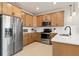 Charming kitchen featuring stainless steel appliances, light wood cabinets, and bright white countertops at 4564 Maple Waltz Aly, Clermont, FL 34714