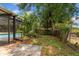Overgrown backyard featuring a pool behind a screen and a wood fence enclosing the greenery at 611 Lakespur Ln, Altamonte Springs, FL 32714