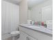 Well-lit bathroom with a single sink vanity, shower with curtain, and granite countertops at 8833 Cruden Bay Ct, Davenport, FL 33896