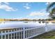 Tranquil lake view framed by a classic white picket fence on a sunny day at 10642 Cloudview Dr, Orlando, FL 32825