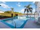 Backyard pool and spa overlooking serene lakefront view with palm trees and lush landscaping at 10642 Cloudview Dr, Orlando, FL 32825