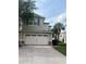 Two-story tan home with a large two-car garage and brick paver driveway at 1122 Priory Cir, Winter Garden, FL 34787