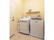 Well-lit laundry room with modern white washer and dryer, shelving, and tiled floor at 14741 Sapodilla Dr, Orlando, FL 32828