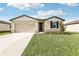 Charming single-story home boasts a well-manicured lawn and inviting neutral exterior with stone accents at 1737 Forest Run Ln, Auburndale, FL 33823