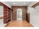 Spacious walk-in closet with custom shelving, wood flooring, and brick arched doorway to the ensuite bathroom at 1741 Palmer Ave, Winter Park, FL 32789