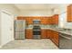 Well-lit kitchen boasts stainless steel appliances, wood cabinets, and stylish tile flooring at 2028 Donegan Pl, Orlando, FL 32826