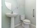 Well-lit half bathroom featuring a pedestal sink, a round mirror, and a comfort height toilet at 2061 Rush Bay Way, Orlando, FL 32824