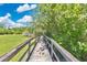 Wooden boardwalk through a community park with lush green surroundings and a clear blue sky at 2460 Worthington Rd, Maitland, FL 32751