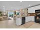 Open-concept kitchen with white cabinets, black appliances, and a kitchen island overlooking the living and dining areas at 316 Primrose Dr, Davenport, FL 33837