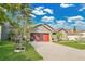 Beautiful home exterior with green lawn and a red garage door under a sunny sky at 321 Thomasdale Ave, Haines City, FL 33844