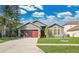 Charming home featuring a well-maintained lawn, red garage door, and lush landscaping at 321 Thomasdale Ave, Haines City, FL 33844