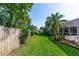 Well-manicured backyard featuring lush green grass, a wooden fence, and mature trees, creating a private outdoor space at 341 Sprucewood Rd, Lake Mary, FL 32746