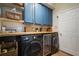 Well-organized laundry room featuring front loading washer and dryer, blue cabinets, open shelves, and butcher block countertop at 402 S Lake Victoria Cir, Deland, FL 32724