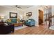 Comfortable living room features wood floors, a teal sofa and armchair, and neutral paint at 402 S Lake Victoria Cir, Deland, FL 32724