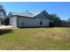 View of home's siding, roof, and grassy backyard with wood fence and clear sky at 549 Silvergate Loop, Lake Mary, FL 32746