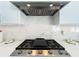 Close-up of a modern gas cooktop and range hood against a white quartz backsplash, showcasing high-end kitchen details at 601 Green Briar Blvd, Altamonte Springs, FL 32714