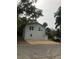 Two-story grey home featuring a gravel driveway and well-maintained landscaping, all nestled under mature trees at 647 Madison Ave, Daytona Beach, FL 32114