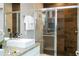 A bathroom is decorated with granite countertop and glass shower with brown tile at 7572 Sunny Dreams Ln, Kissimmee, FL 34747