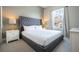 A bedroom featuring a plush queen-sized bed with a gray upholstered headboard and views of the neighborhood at 7572 Sunny Dreams Ln, Kissimmee, FL 34747