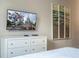 A cozy bedroom featuring a dresser with a wall-mounted TV and beach-themed art above the bed at 7572 Sunny Dreams Ln, Kissimmee, FL 34747