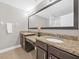 Bathroom featuring double vanity with granite counters, dark wood cabinets, and a large mirror at 8215 Roseville Blvd, Davenport, FL 33896