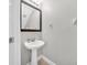 Charming powder room with pedestal sink, framed mirror, updated fixtures, and a clean, modern design at 8215 Roseville Blvd, Davenport, FL 33896