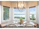 Bright breakfast nook featuring bay windows with scenic waterfront views and a decorative chandelier above at 9724 Chestnut Ridge Dr, Windermere, FL 34786