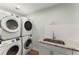 Bright laundry room featuring stacked washer and dryer units with sink at 9724 Chestnut Ridge Dr, Windermere, FL 34786