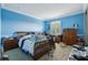 Bright blue bedroom with shuttered windows, a wooden bed, and carpet at 9736 Hatton Cir, Orlando, FL 32832
