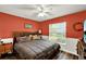 Inviting bedroom with warm orange walls, complemented by a ceiling fan and a view through a bright window at 1608 Victoria Way, Winter Garden, FL 34787