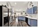 Bright kitchen featuring stainless steel appliances, blue cabinets, and hardwood floors with a view to the dining area at 1608 Victoria Way, Winter Garden, FL 34787