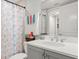 Well-lit bathroom featuring a clean white sink, vanity, and patterned shower curtain, providing a fresh and functional space at 1 Riverwalk Dr # 303, New Smyrna Beach, FL 32169