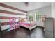Charming bedroom featuring striped accent wall, white trim and ample natural light from two windows at 10252 Kristen Park Dr, Orlando, FL 32832